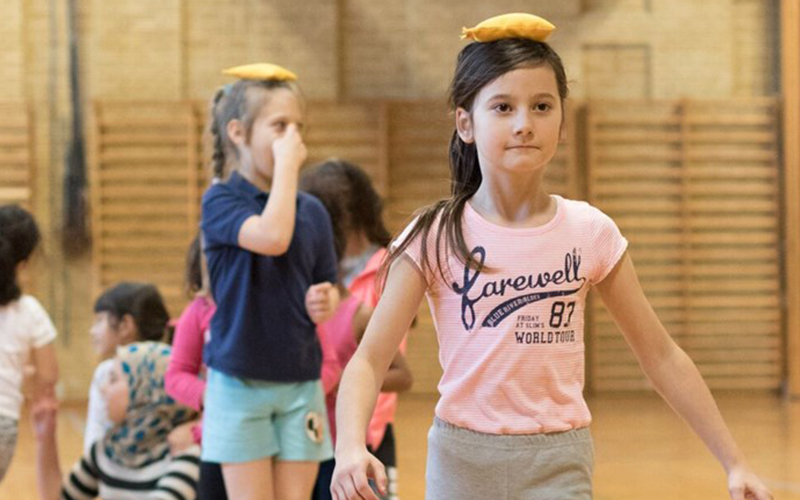 Børn der dyrker gymnastik, pige med lyserød T-shirt og rispose på hovedet